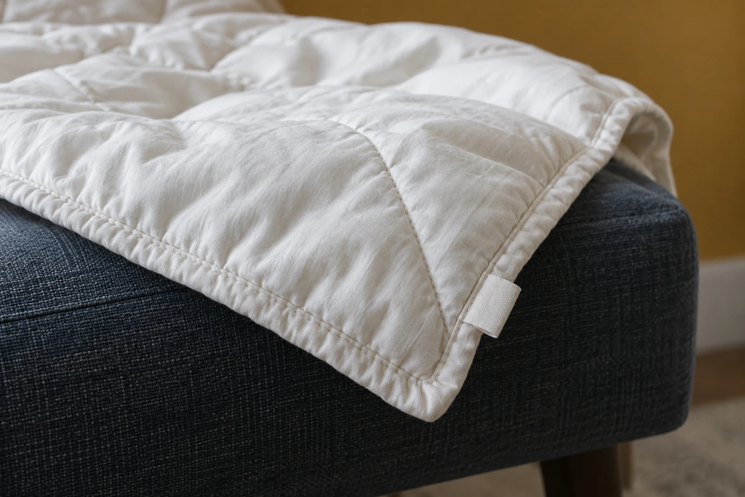 Bound comforter corner with quilt stitching and the blank reverse of a care tag