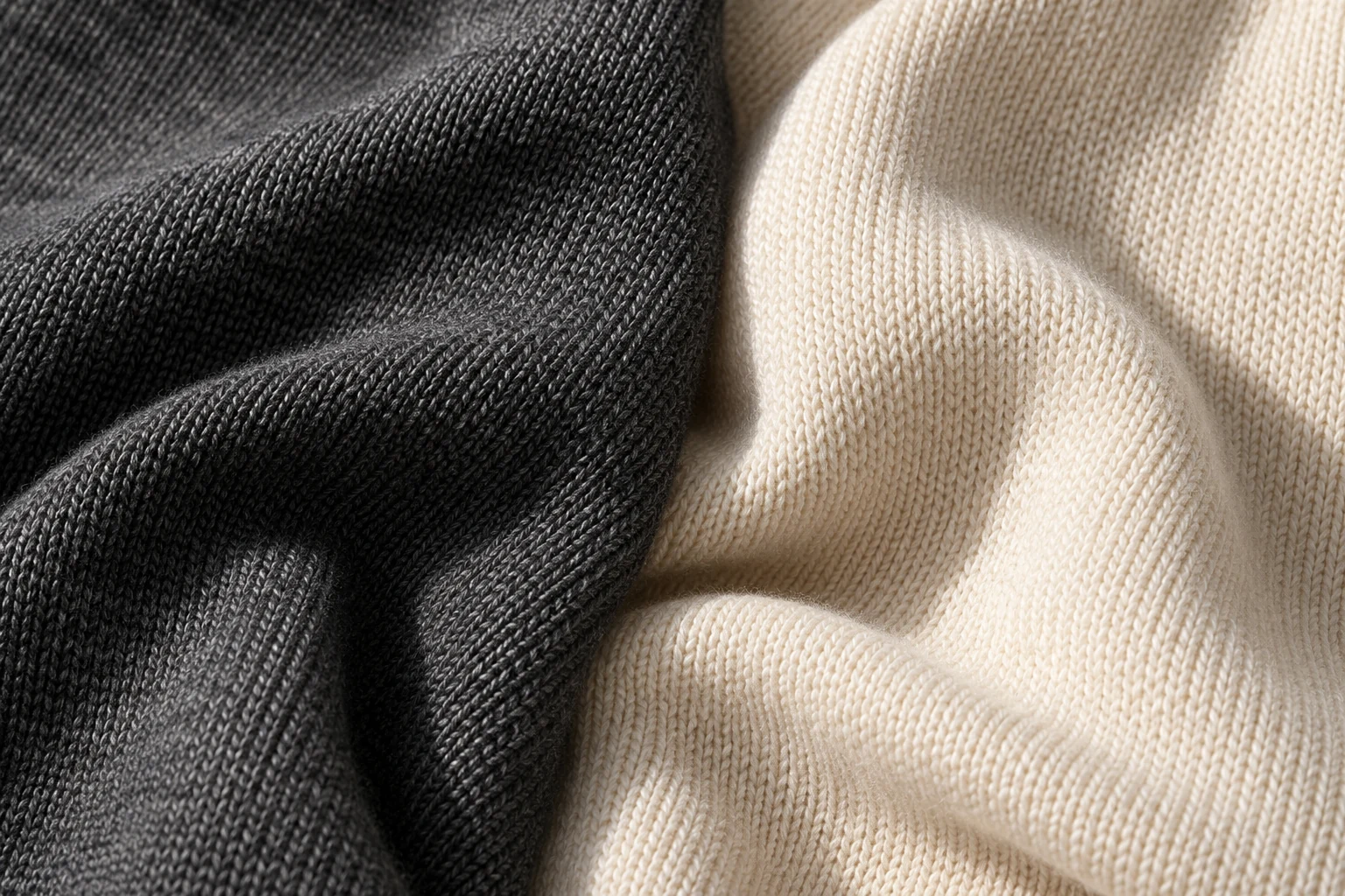 Close view of smooth charcoal knit beside a cream knit with a soft surface halo.