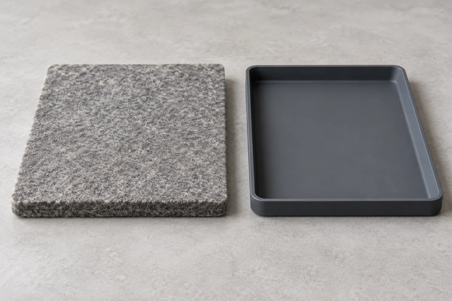 Gray wool pressing mat beside a separate shallow tray on a work surface.